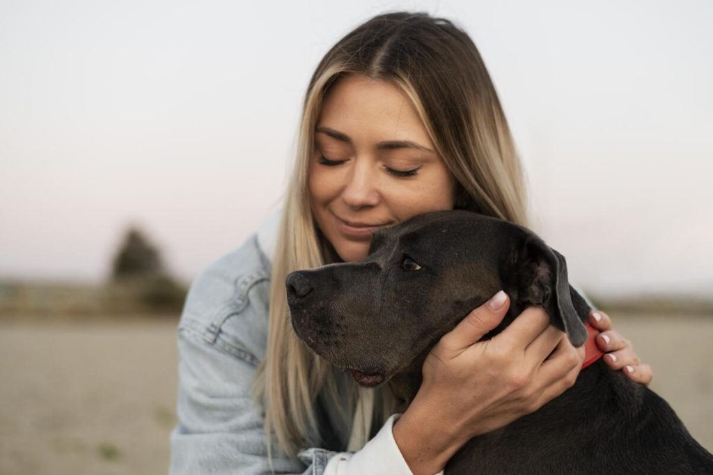 Mulher sorrindo enquanto abraça um cachorro