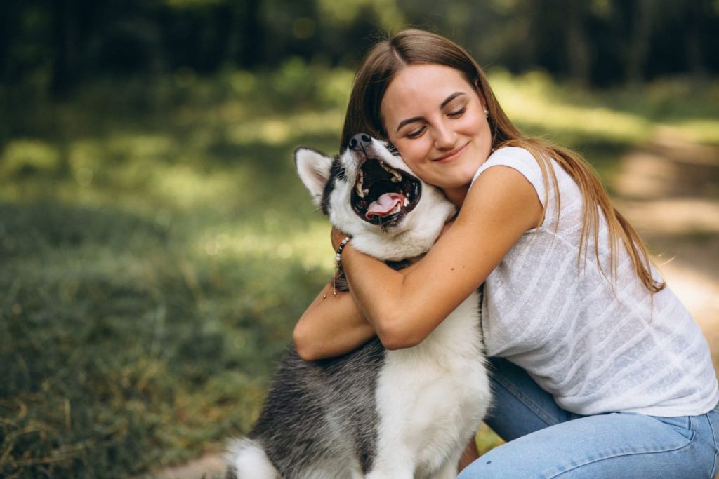 Mulher abraçando cachorro feliz em parque