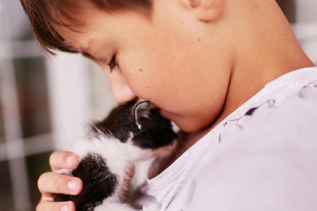 Criança abraçando um gato preto e branco