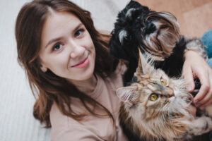 Mulher segurando cão e gato em casa